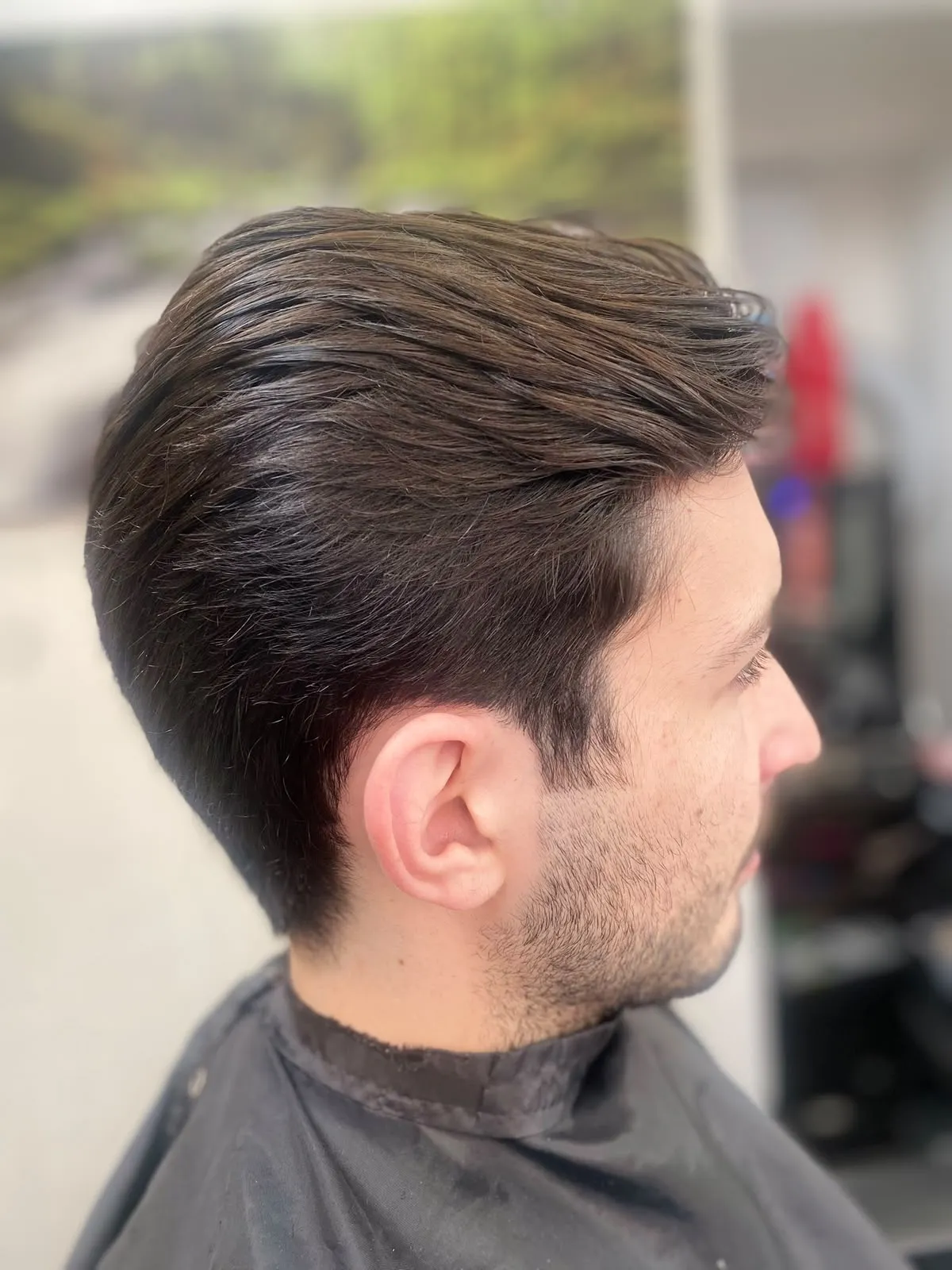 Corte de hombre desvanecido a los lados y peinado hacia atrás, de perfil.