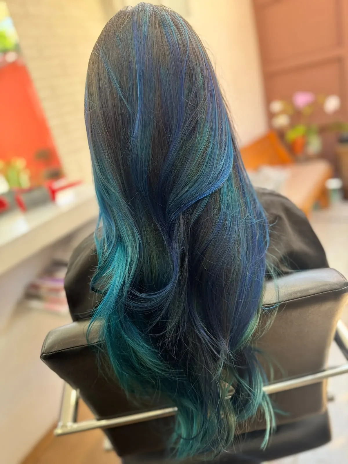 Melena larga con diseño de color en azules y verdes degradados, vista desde atrás.