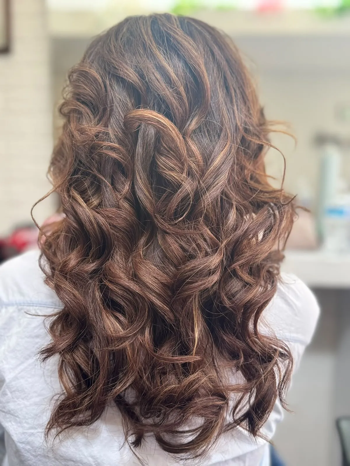 Ondas definidas en melena castaña con reflejos caramelo, vistas desde atrás.