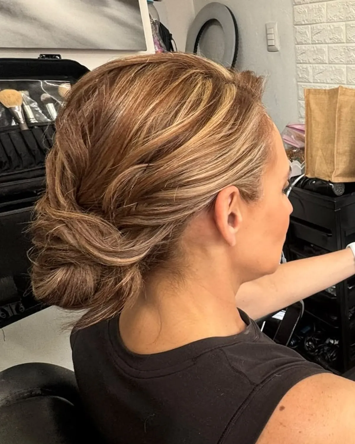Chongo bajo texturizado sobre cabello con luces rubias, visto desde atrás.