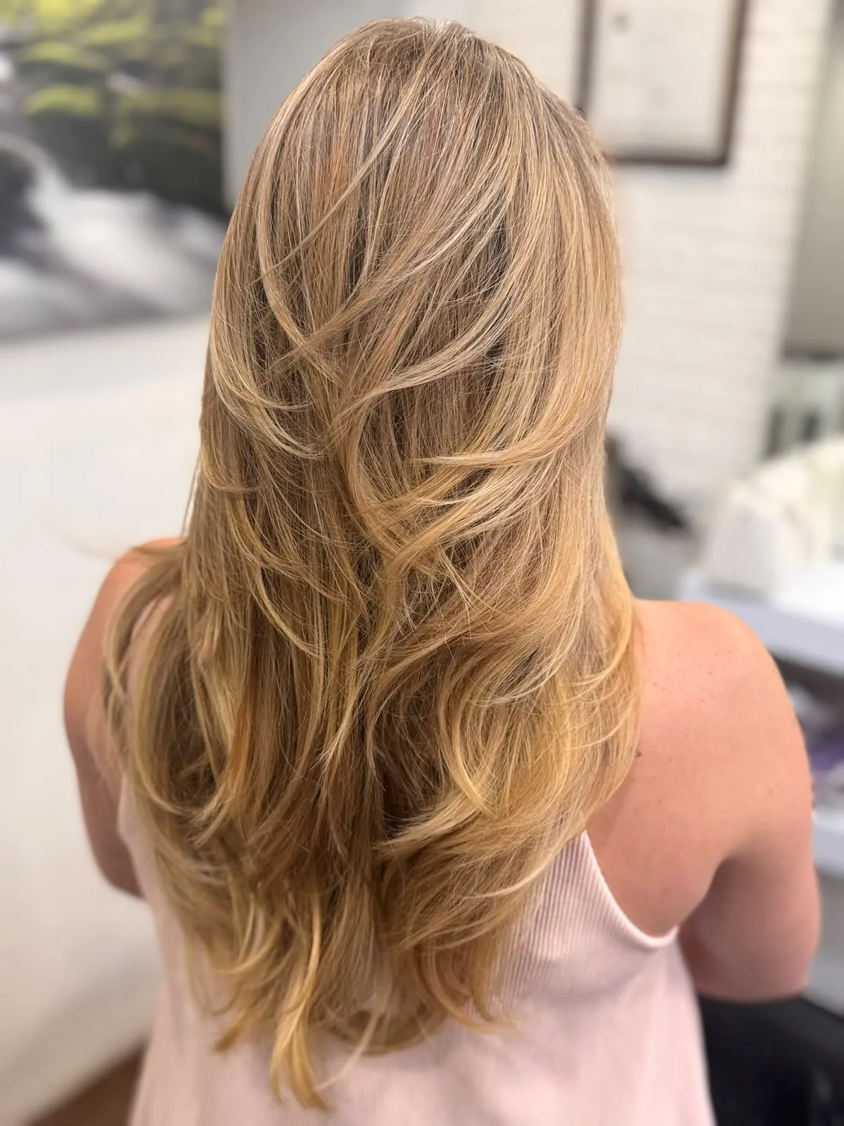 Melena rubia larga en capas con movimiento, vista desde atrás.